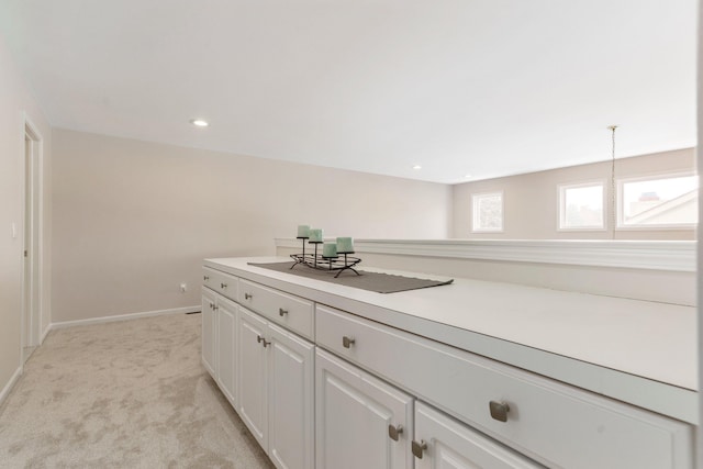 interior space featuring white cabinetry, light carpet, and hanging light fixtures