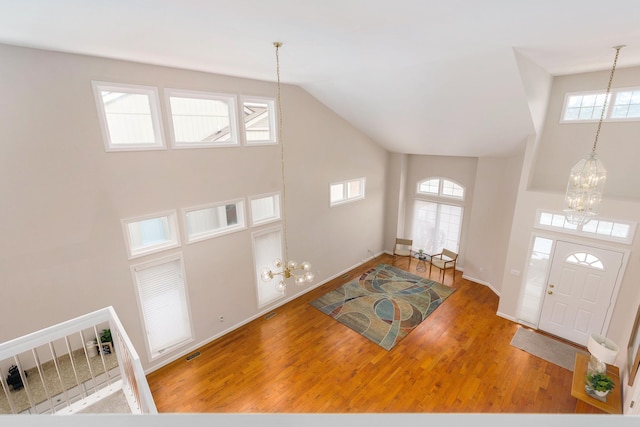 foyer featuring hardwood / wood-style floors, plenty of natural light, high vaulted ceiling, and a notable chandelier