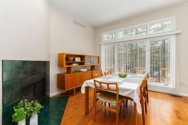 dining space with wood-type flooring and a tile fireplace