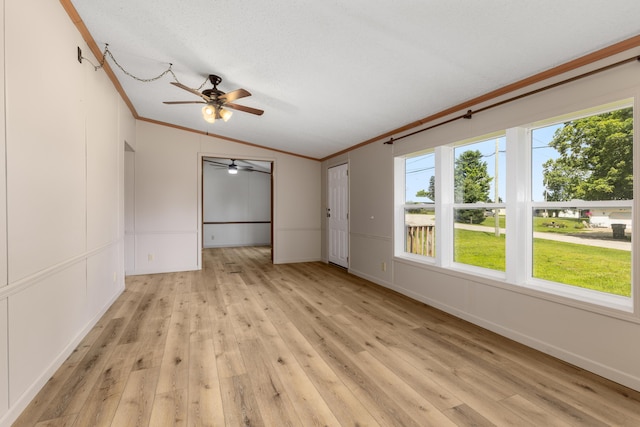 spare room with light hardwood / wood-style floors, a textured ceiling, ornamental molding, and lofted ceiling