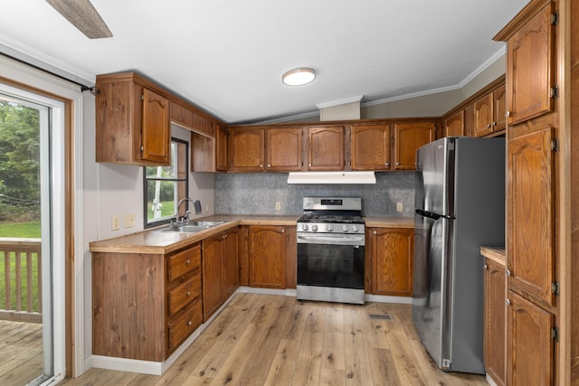 kitchen with appliances with stainless steel finishes, backsplash, light wood-type flooring, lofted ceiling, and sink