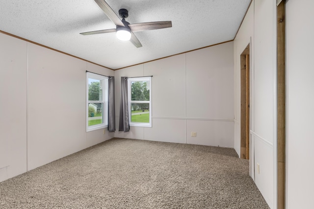 carpeted spare room with ceiling fan, vaulted ceiling, crown molding, and a textured ceiling