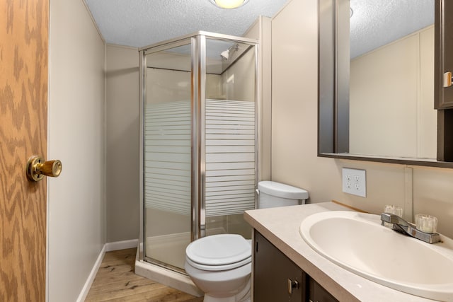 bathroom with a textured ceiling, toilet, walk in shower, and vanity