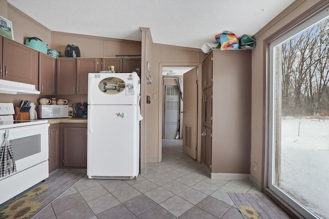 kitchen featuring white appliances, a textured ceiling, and light tile patterned floors