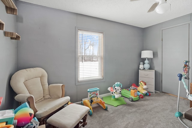 playroom featuring ceiling fan, carpet flooring, and a textured ceiling