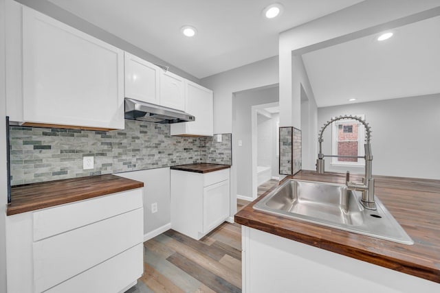 kitchen with white cabinetry, wooden counters, ventilation hood, light wood-type flooring, and sink