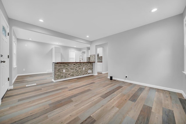 unfurnished living room featuring light hardwood / wood-style floors and sink