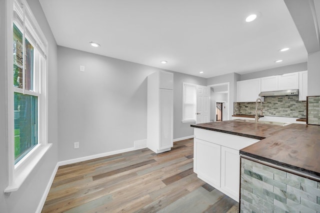 kitchen with decorative backsplash, plenty of natural light, and white cabinetry