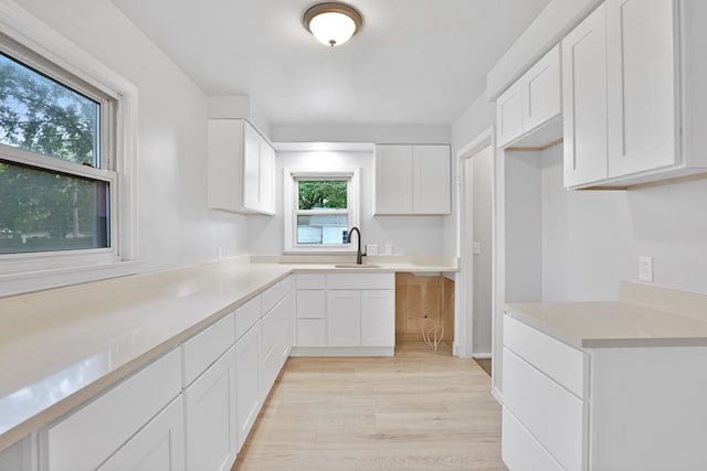 kitchen featuring a healthy amount of sunlight, sink, white cabinetry, and light hardwood / wood-style floors