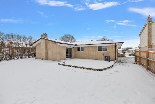 snow covered back of property featuring central AC unit