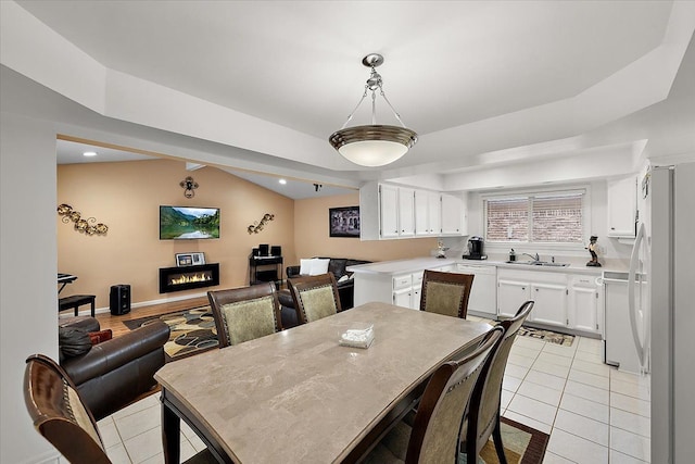 dining space with lofted ceiling, sink, and light tile patterned floors