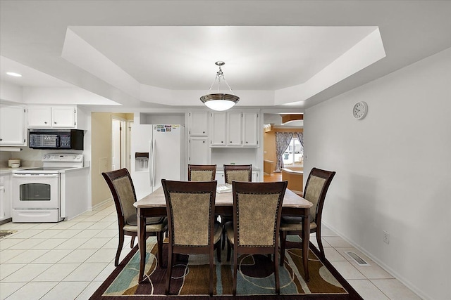 tiled dining room featuring a tray ceiling