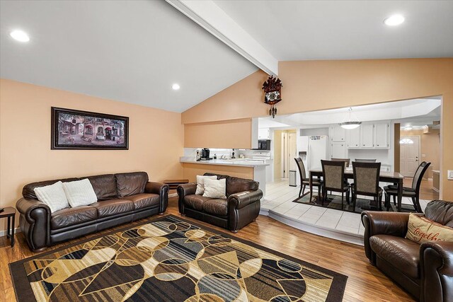 living room featuring vaulted ceiling with beams and light wood-type flooring