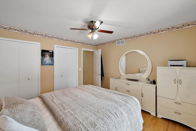 bedroom with two closets, ceiling fan, and light hardwood / wood-style floors