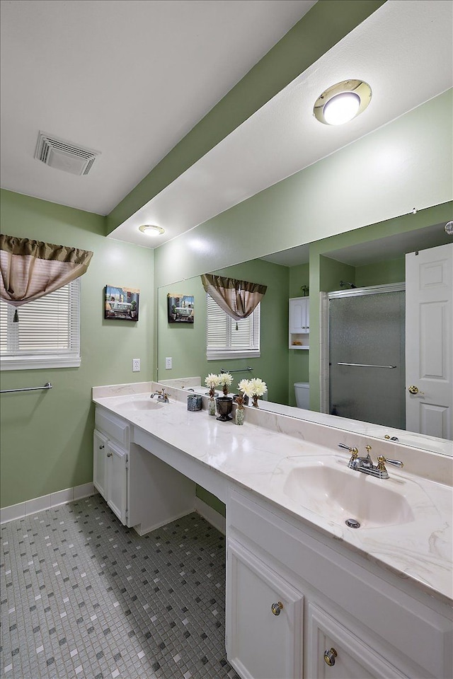 bathroom featuring tile patterned floors, vanity, toilet, and a shower with door