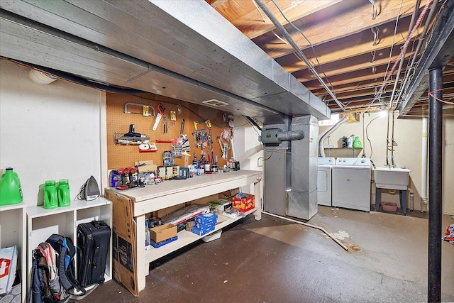 basement featuring sink, washer and clothes dryer, and a workshop area