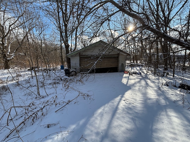 snowy yard featuring a garage and an outbuilding