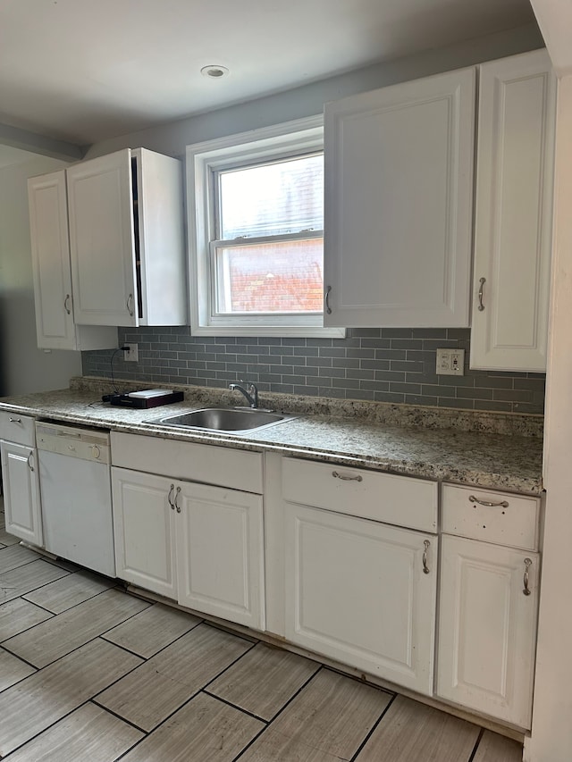 kitchen with sink, white cabinetry, backsplash, and dishwasher