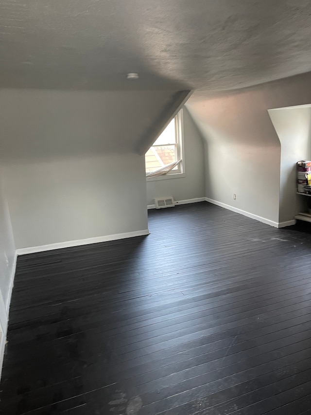 bonus room featuring a textured ceiling, dark hardwood / wood-style floors, and lofted ceiling