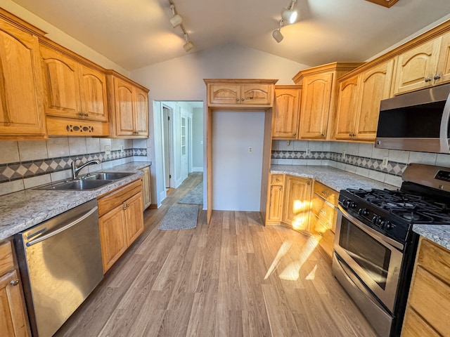 kitchen with decorative backsplash, sink, light wood-type flooring, stainless steel appliances, and light stone counters