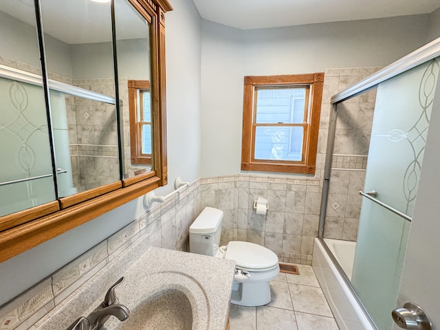 full bathroom with toilet, vanity, tile walls, tile patterned floors, and enclosed tub / shower combo