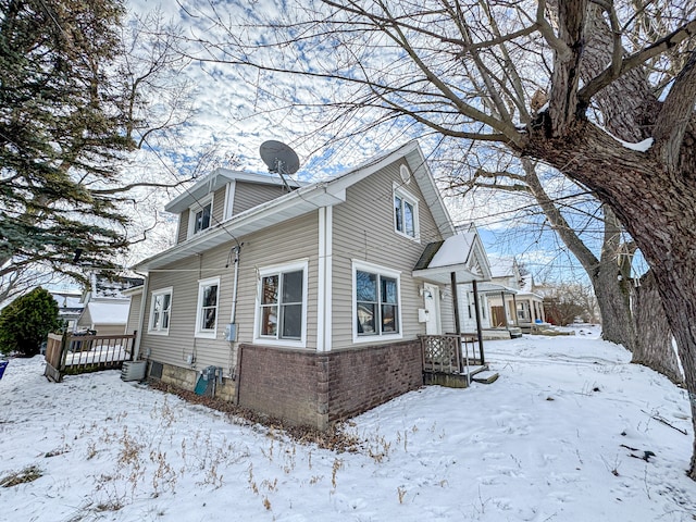 snow covered property with central air condition unit and a wooden deck