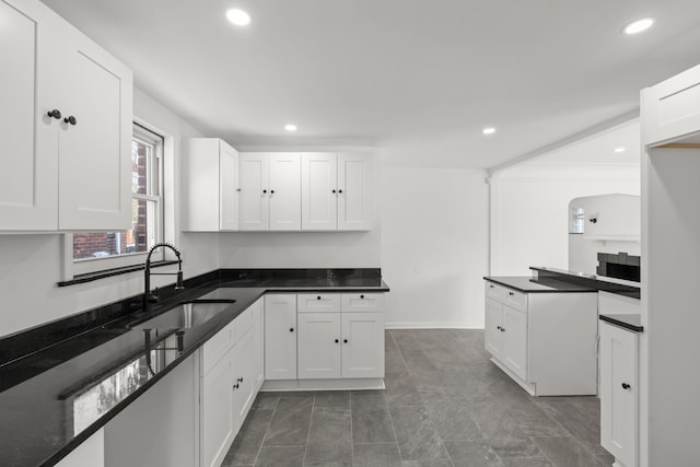 kitchen with dark tile patterned flooring, sink, dark stone countertops, and white cabinetry