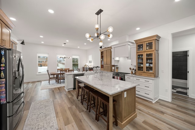 kitchen featuring white cabinets, a kitchen island, stainless steel appliances, hanging light fixtures, and a breakfast bar area