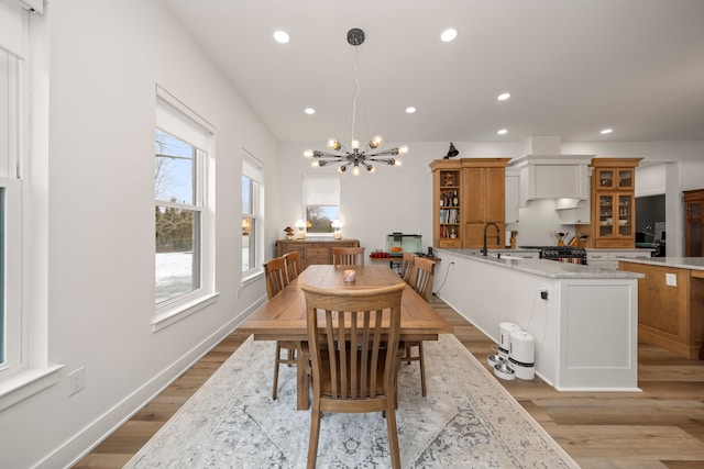 dining room with light wood-type flooring, a chandelier, and sink