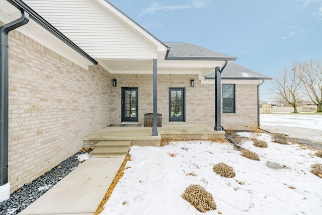 snow covered property entrance featuring covered porch