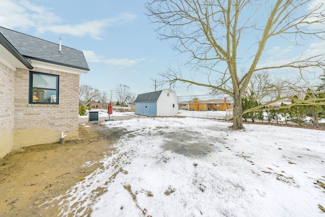 snowy yard featuring a storage unit