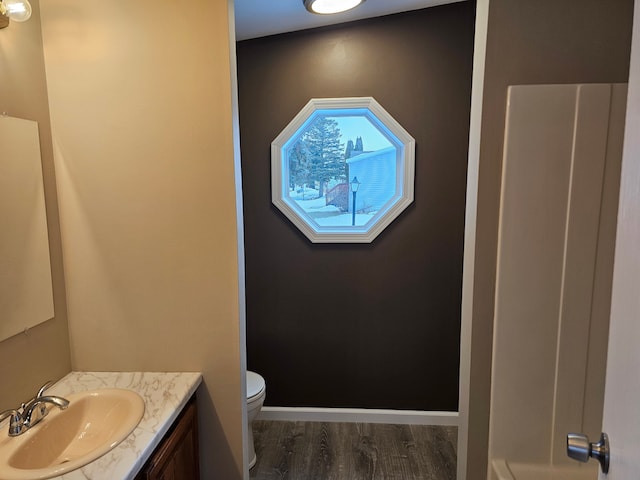 bathroom with toilet, hardwood / wood-style floors, and vanity