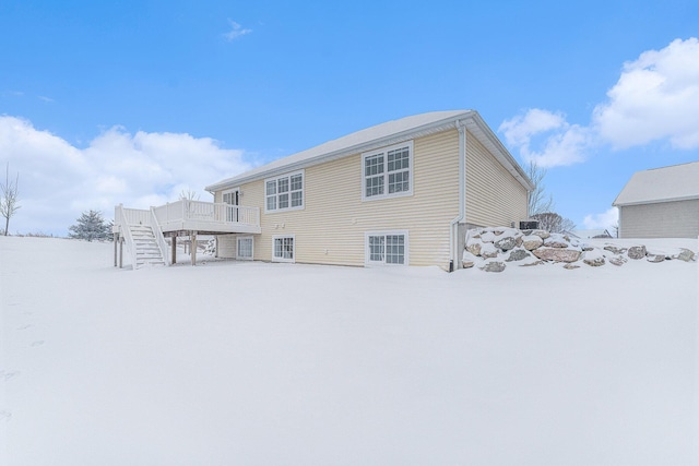 snow covered back of property with a deck