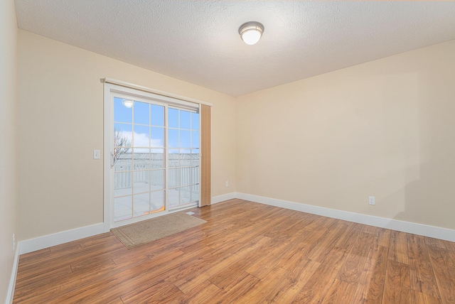 spare room with a textured ceiling and hardwood / wood-style flooring
