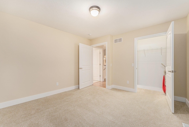 unfurnished bedroom with light carpet and a closet