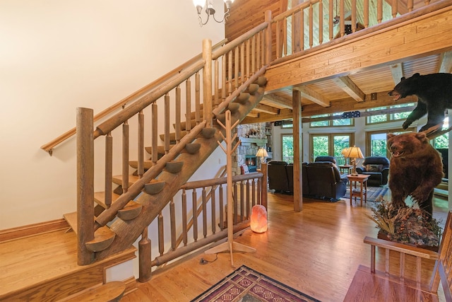 stairs featuring a stone fireplace, hardwood / wood-style floors, and beam ceiling