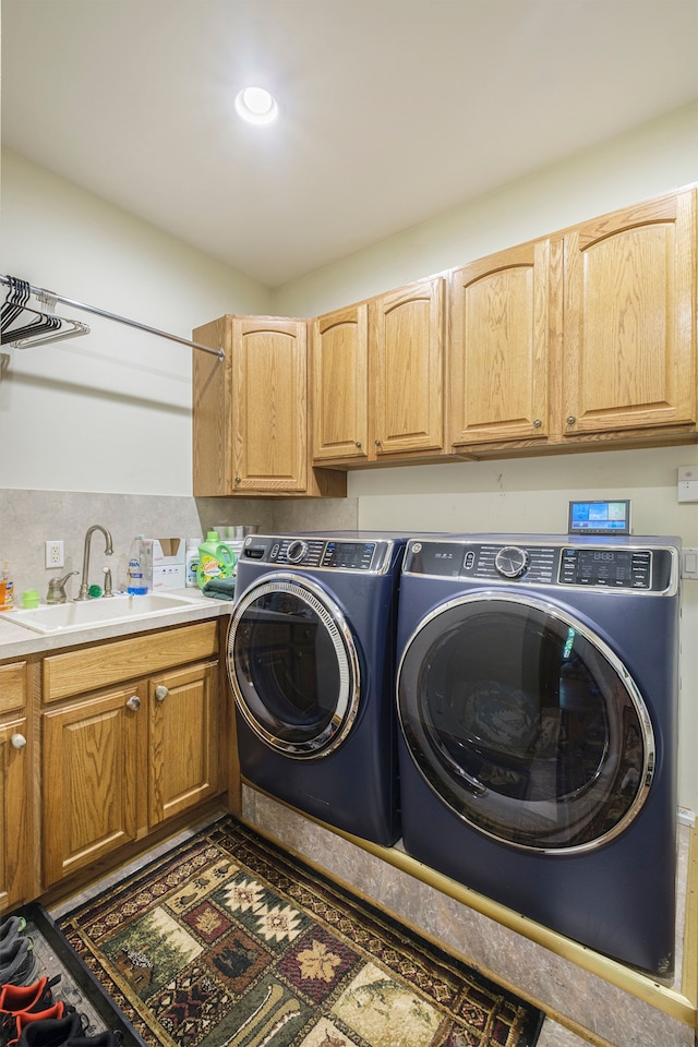 clothes washing area with cabinets, washer and clothes dryer, and sink