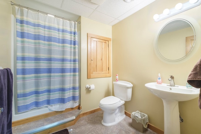 bathroom with sink, curtained shower, a paneled ceiling, and toilet