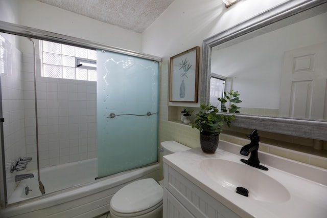 full bathroom with combined bath / shower with glass door, vanity, toilet, and a textured ceiling