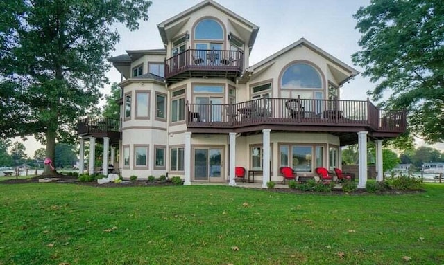 back of property featuring a balcony and a yard