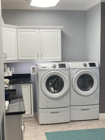 laundry area with cabinets, light tile patterned flooring, washer and clothes dryer, and ornamental molding