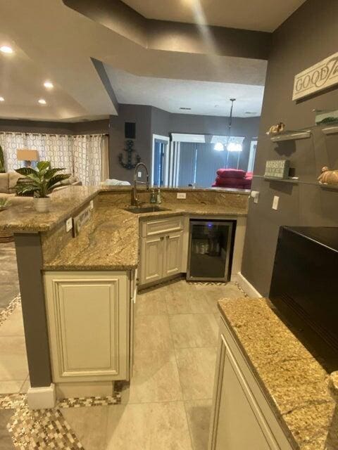 kitchen featuring wine cooler, cream cabinetry, sink, and a kitchen island