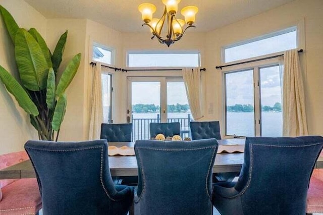 dining space featuring a water view, french doors, and a chandelier