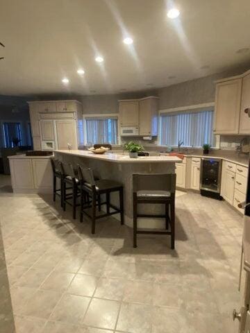 kitchen with light tile patterned floors, a kitchen bar, and beverage cooler