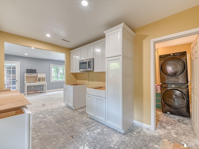 kitchen with white cabinetry and stacked washer / drying machine