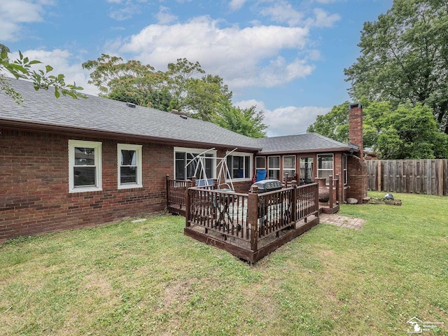 rear view of house with a wooden deck and a lawn