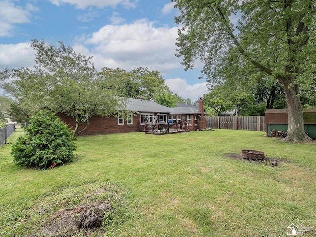 view of yard with a deck, a fire pit, and a storage unit