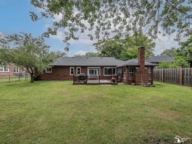 back of property with a wooden deck and a lawn