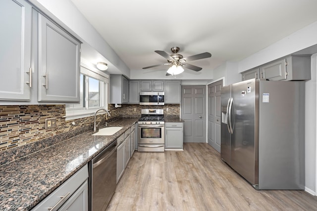 kitchen featuring sink, gray cabinetry, stainless steel appliances, and dark stone counters