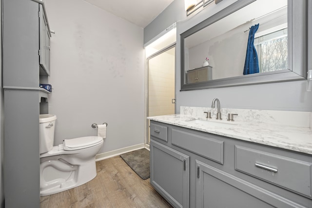 bathroom featuring toilet, walk in shower, hardwood / wood-style floors, and vanity